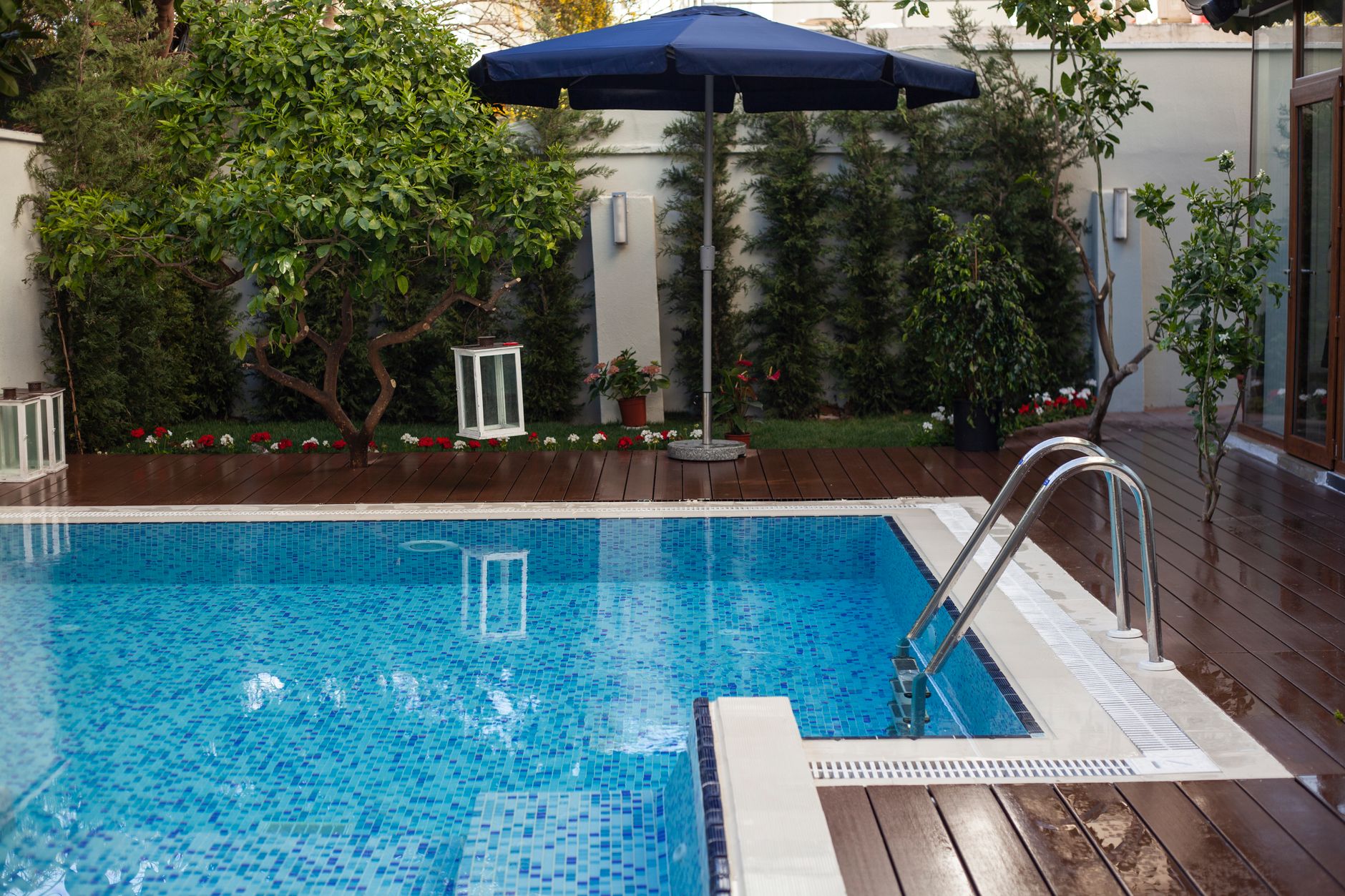 Serene backyard featuring a swimming pool, lush garden, and wooden deck in Antalya, Turkey.