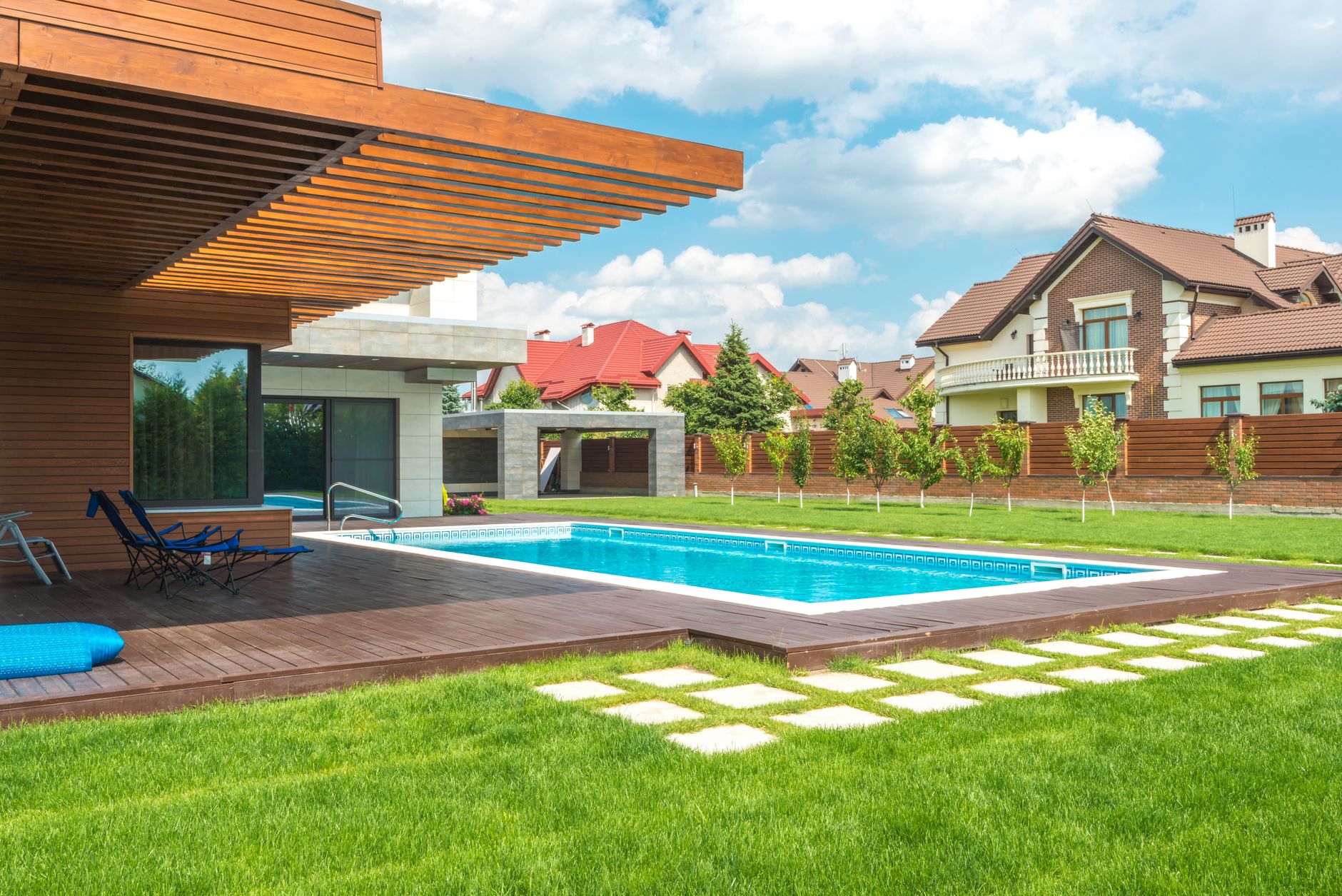 Stunning modern home exterior with a pool and well-maintained backyard under a blue sky.