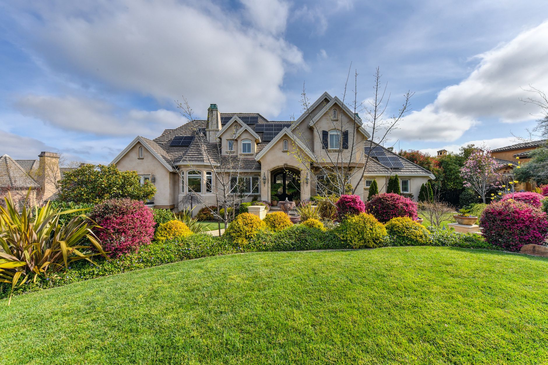 Elegant suburban house surrounded by a lush, landscaped garden on a sunny day.