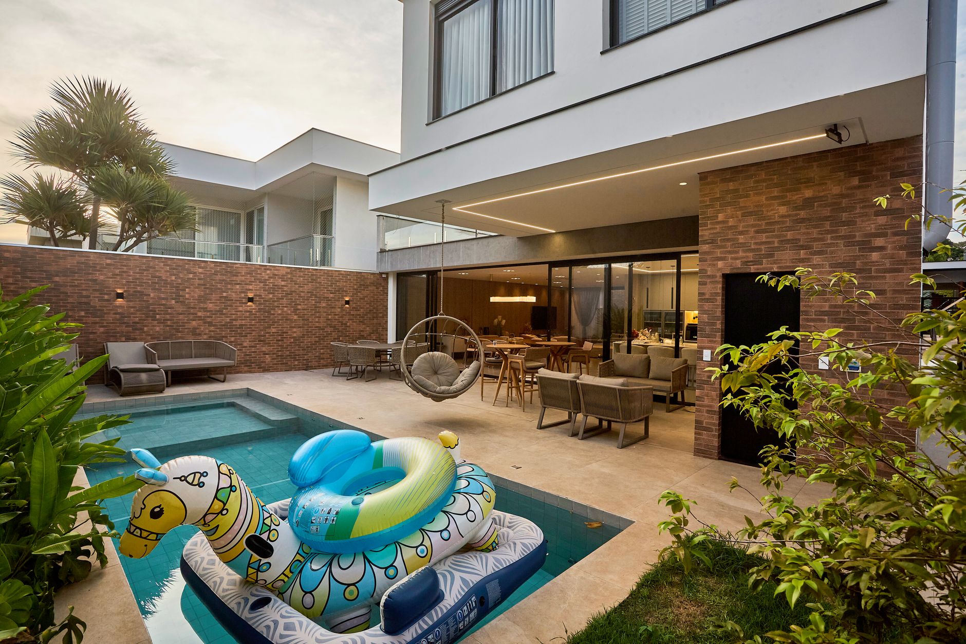 Tranquil backyard retreat featuring a pool, seating area, and creative inflatable in a modern setting.